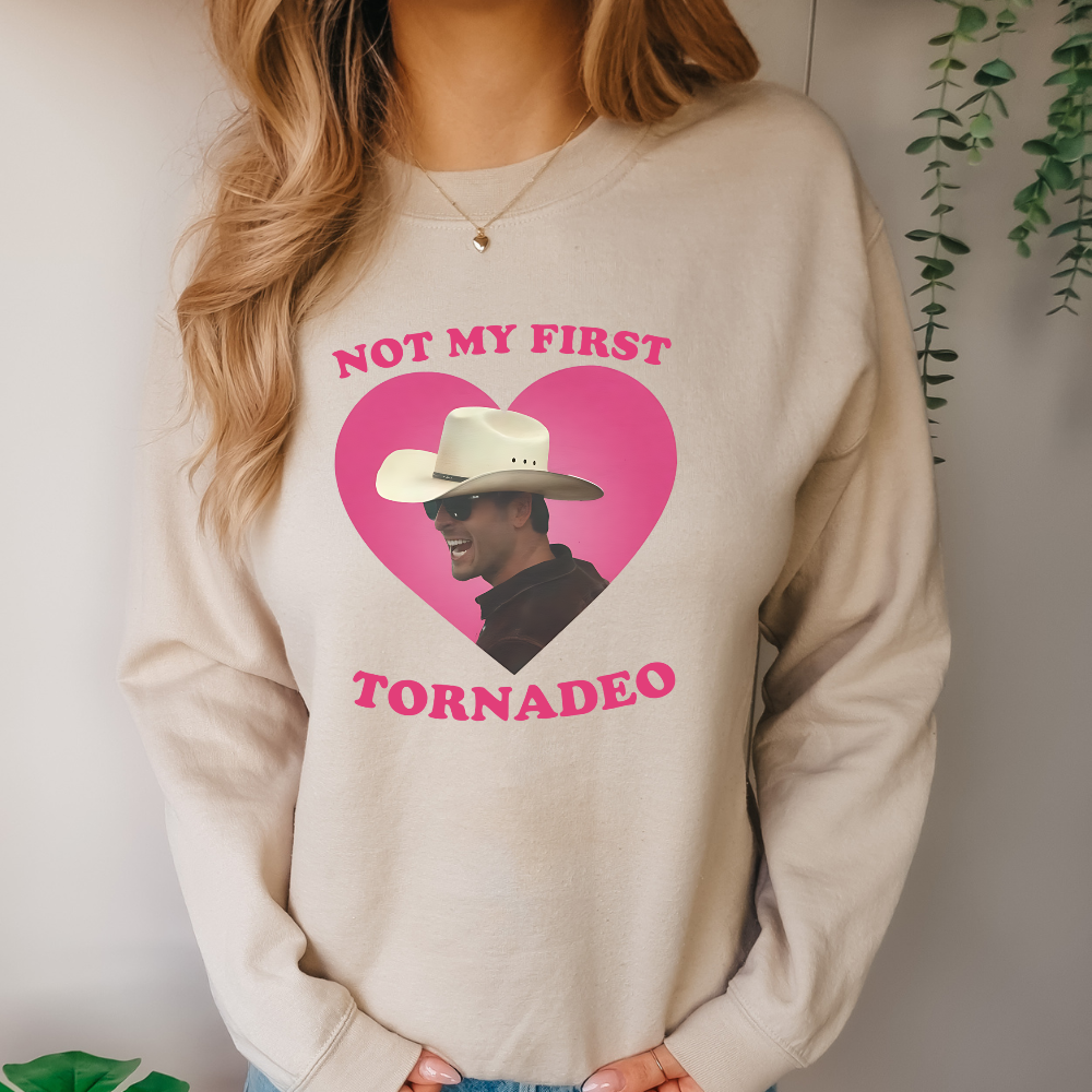 photo of a woman wearing a tan crewneck sweatshirt with a photo of Glen Powell that says not my first tornado. glen powell twister movie fan apparel design