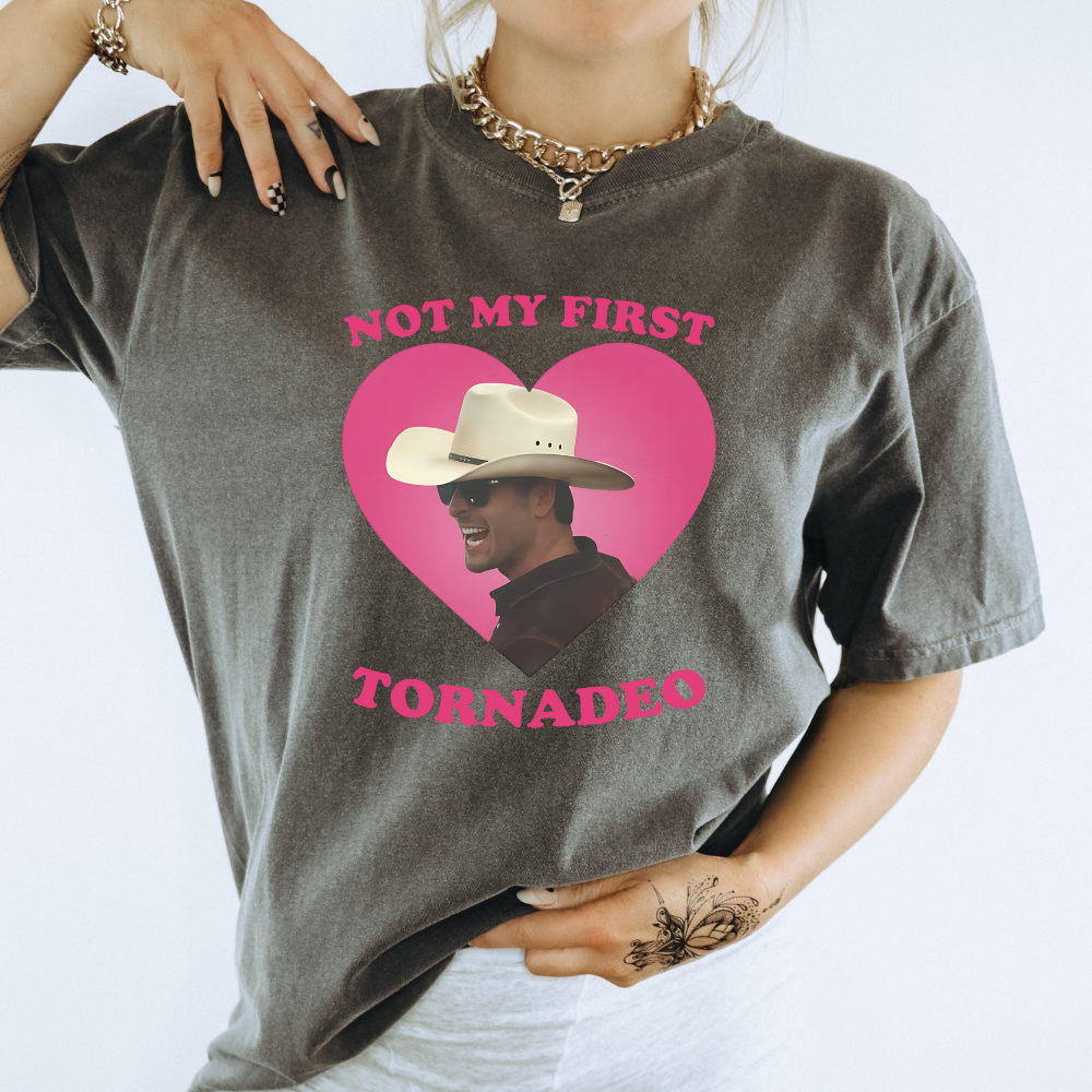 photo of a woman wearing a dark gray short sleeve t-shirt with a photo of Glen Powell that says not my first tornado. glen powell twister movie fan apparel design